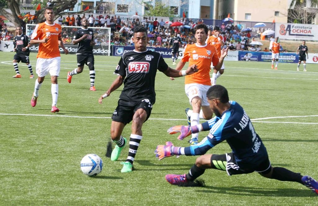 El juvenil Ernesto Trinidad intenta anotar ante la defensa del  portero Alexander Rodriguez del Cibao FC